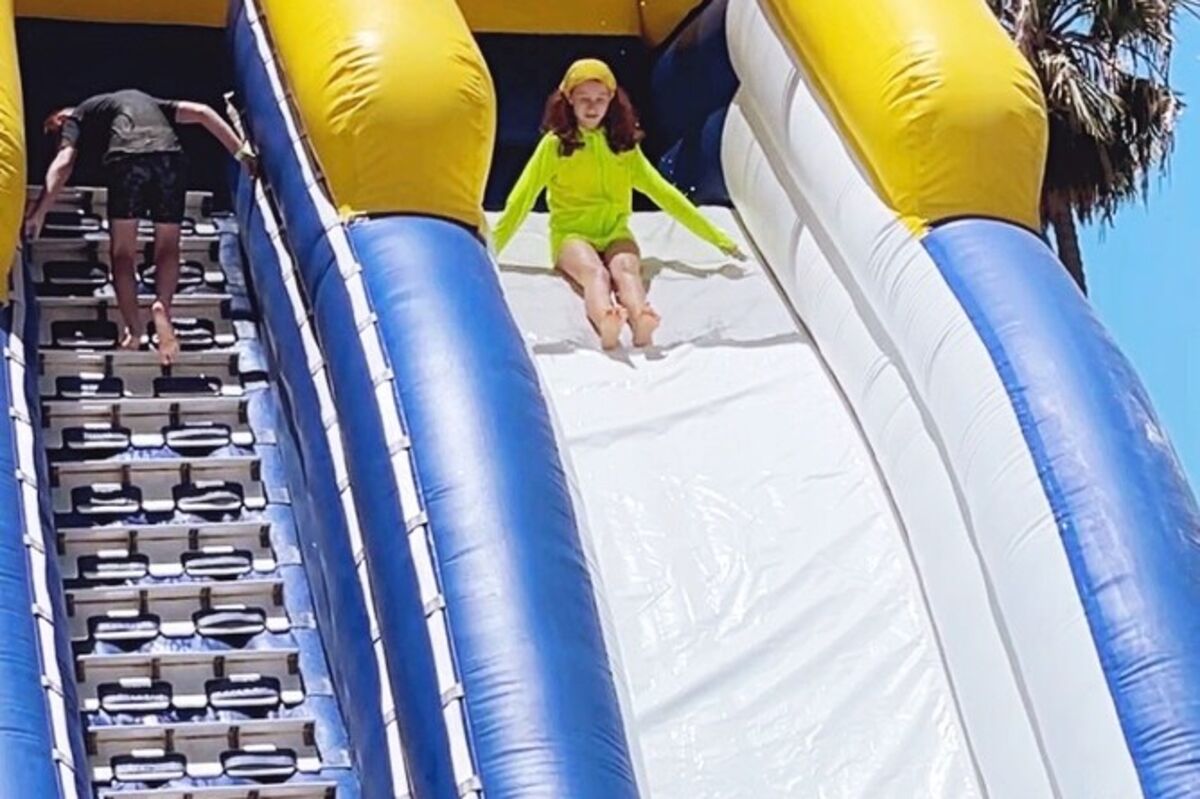 An%20inflatable%20giant%20waterslide%20two%20stories%20tall%20with%20a%20girl%20sliding%20down%2E