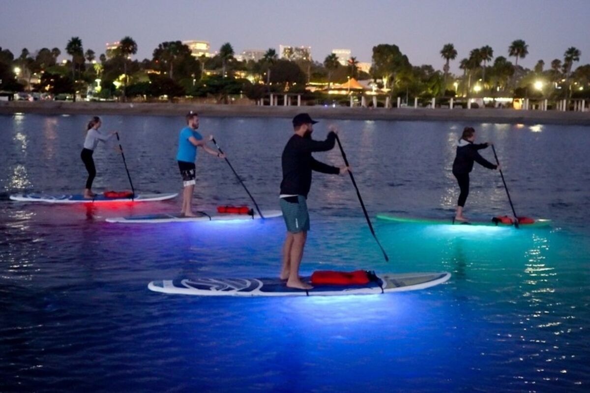 Three people doing nighttime stand up paddleboards in a lagoon