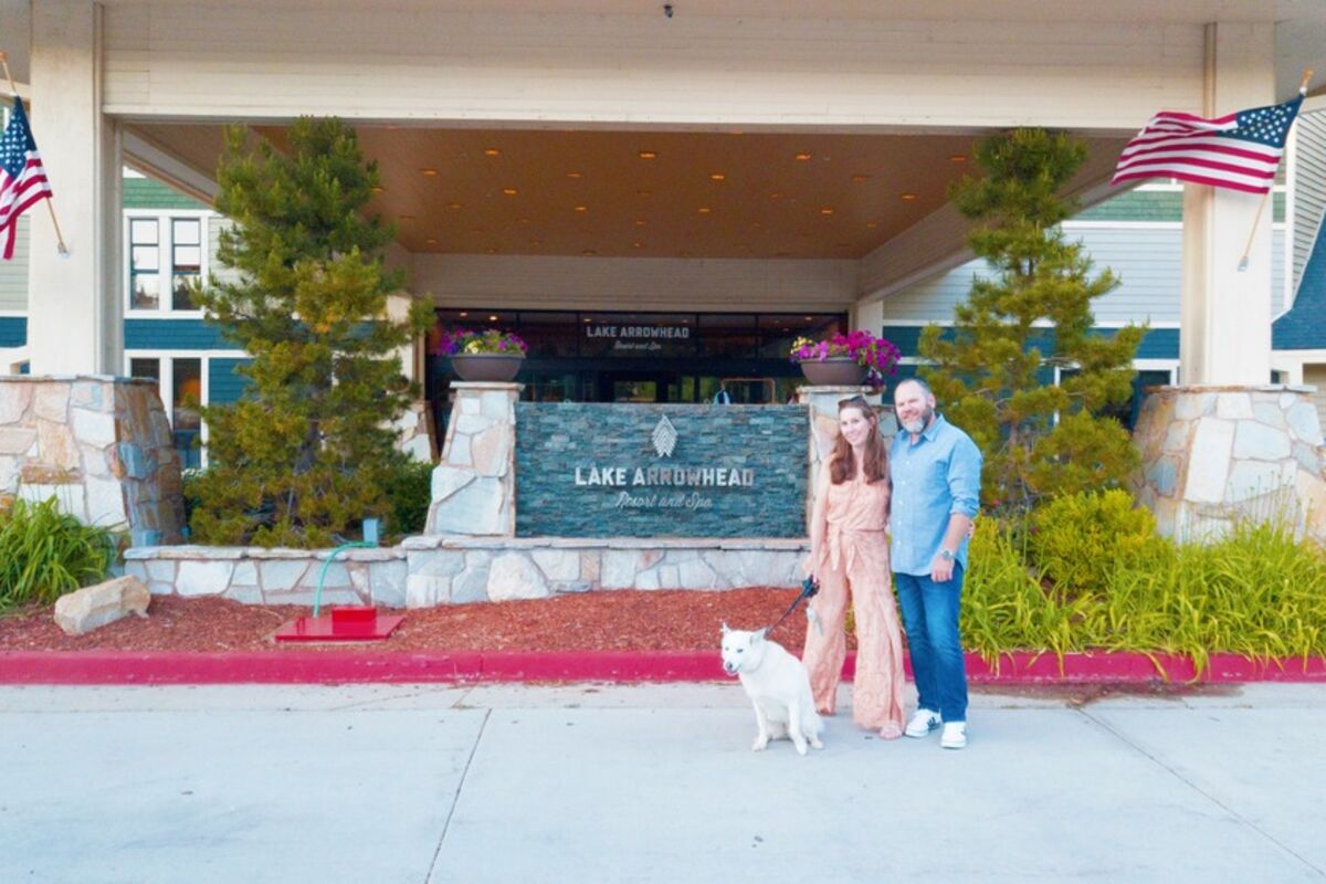 a couple with dog standing in front of resort