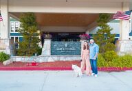 a couple with dog standing in front of resort
