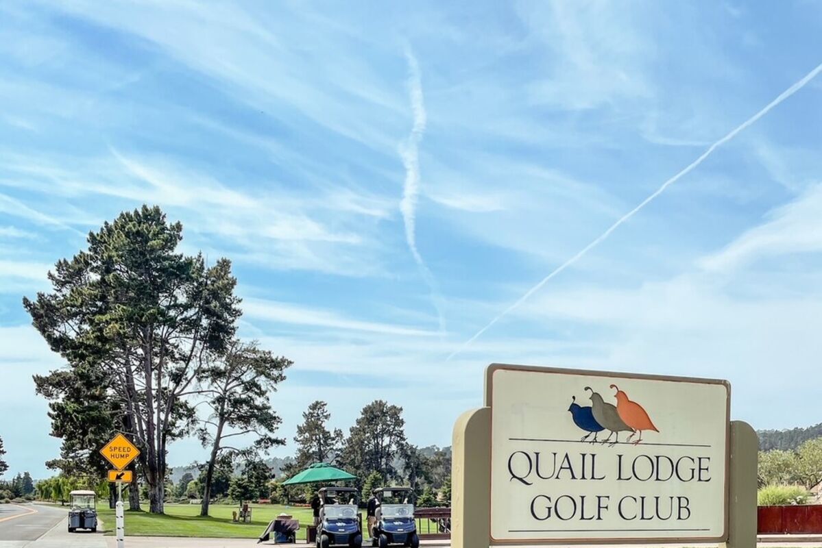 Golf course sign with golf carts in background
